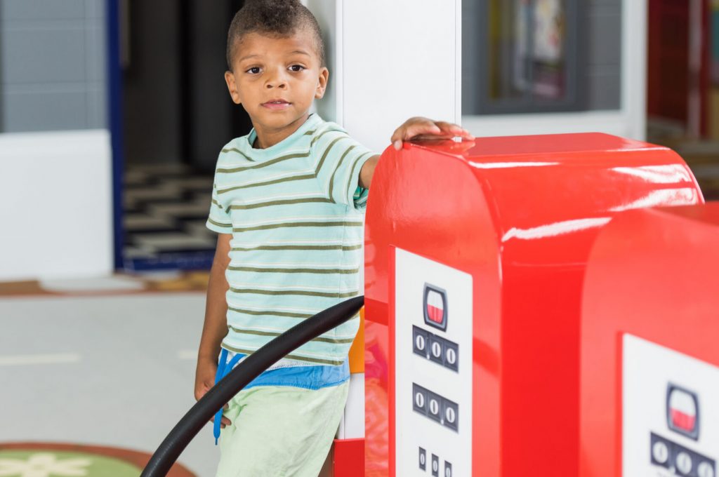 Little boy at gas station at kids game center. Kid having fun indoor. Activity center for kids.